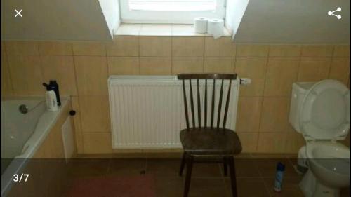 a bathroom with a chair and a toilet and a window at Mansarda in Mýto pod Ďumbierom