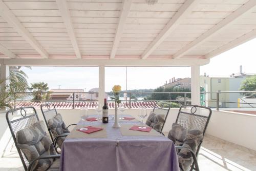 a table with chairs and a bottle of wine on a patio at Rooms and apartments PALMA B&B in Medulin