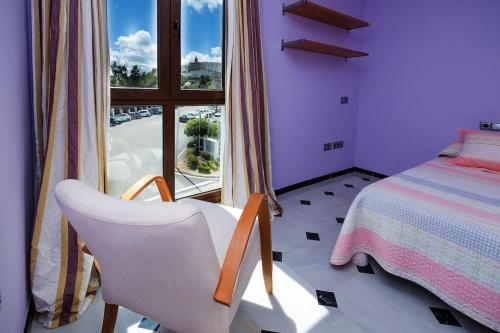ベヘール・デ・ラ・フロンテーラにあるCasa Vejer en altoのベッドルーム1室(白い椅子、ベッド1台、窓付)