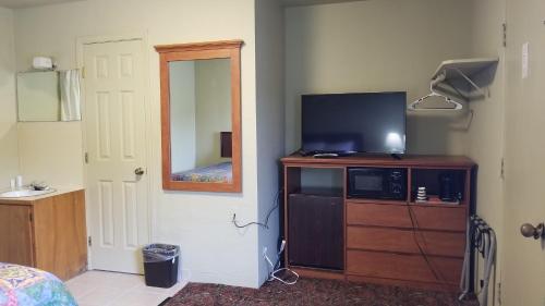 a bedroom with a television on a dresser with a mirror at Quick Stop Motel in Round Prairie