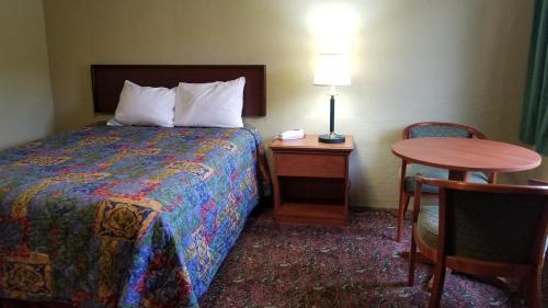 a hotel room with a bed and a table and chair at Quick Stop Motel in Round Prairie