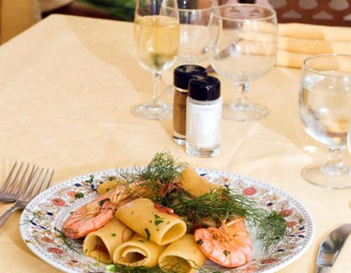 a plate of shrimp and pasta on a table with wine glasses at Le Canne Family Resort & Spa in Ischia