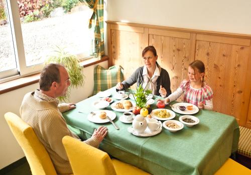 a family sitting at a table eating breakfast at Natur Pur Hotel Unterpichl in Ultimo