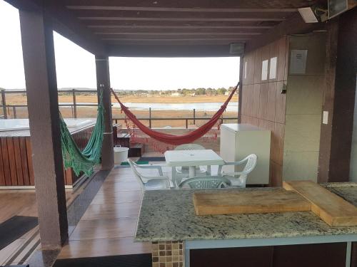 a patio with a table and chairs and a hammock at Casa no Lago de Furnas in Pontevila