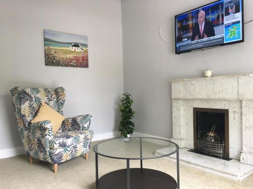 sala de estar con silla, mesa y TV en Donnybrook Townhouse, en Dublín