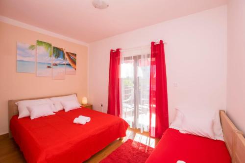 a bedroom with two red beds and a window at Apartments Katarina in Pirovac