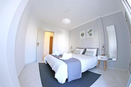 a white bedroom with a large bed and a table at Ferragudo'Spot in Ferragudo