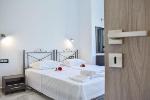 a bedroom with two beds with white sheets and red roses at Katsaros Luxury Apts 5min walk to beach in Tsilivi