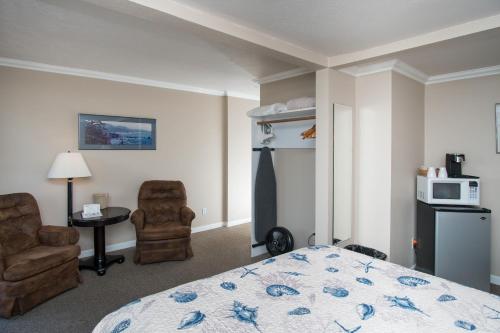 a bedroom with a bed and two chairs and a microwave at Ecola Creek Lodge in Cannon Beach