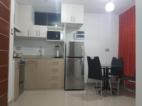 a kitchen with a refrigerator and a table and chairs at Nino´s Residence Departamentos VIP Amoblados in Tacna