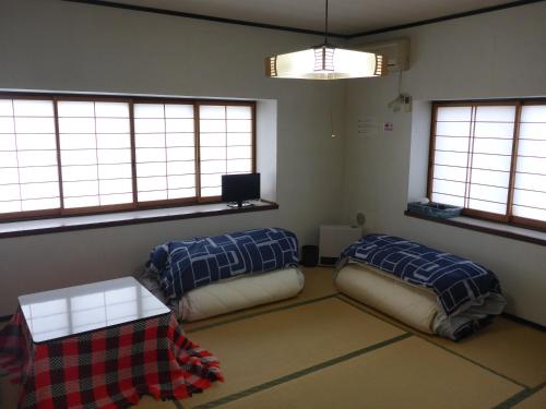 a room with two beds and a table and windows at Nozawa Dream in Nozawa Onsen
