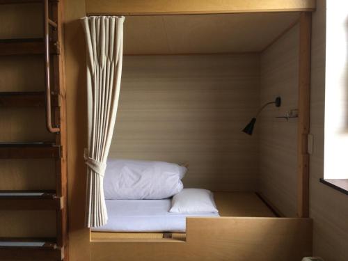 Habitación pequeña con cama en un armario en Niseko Tabi-tsumugi Backpackers, en Kutchan