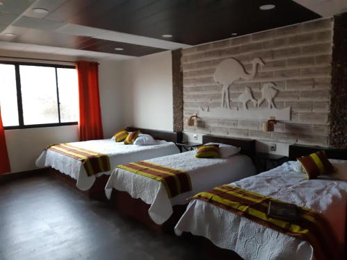 a bedroom with two beds and a brick wall at Hotel Cristales De Sal in Uyuni