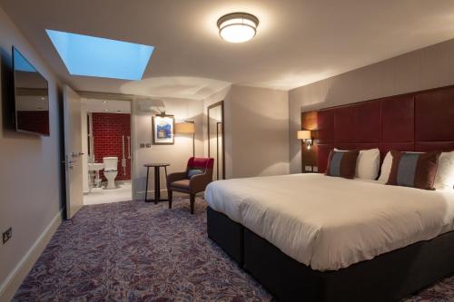 a hotel room with a large bed and a bathroom at Thomas Ingoldsby Wetherspoon in Canterbury