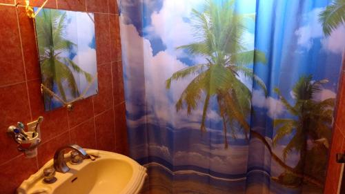 a bathroom with a sink and a palm tree shower curtain at Casa Magua in Bucerías