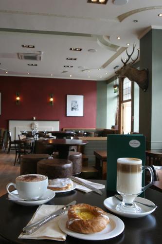 a table with two plates of food and cups of coffee at Columba Hotel Inverness by Compass Hospitality in Inverness
