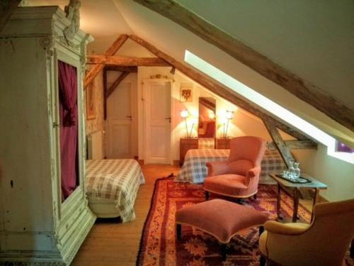 a attic room with a bed and a couch and chair at Domaine du Have in Sainte-Christie-dʼArmagnac