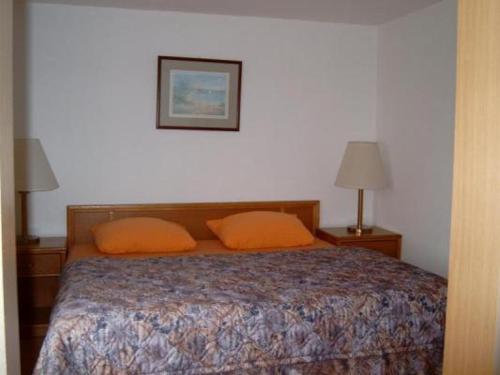 ボルンにあるFeWo1のベッドルーム1室(オレンジ色の枕2つ、ベッド1台付)