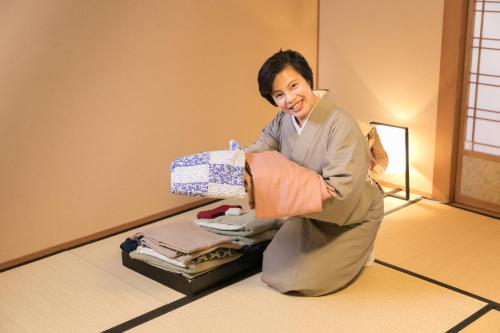 a man in a room holding a box of clothes at Honjin Hiranoya Kachoan in Takayama
