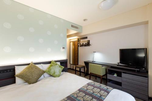 a hotel room with a bed and a desk and a television at Takamatsu Tokyu REI Hotel in Takamatsu