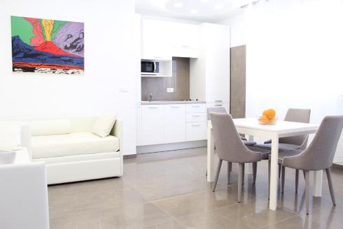 a white dining room with a white table and chairs at Mondo Suites Apartments in Naples