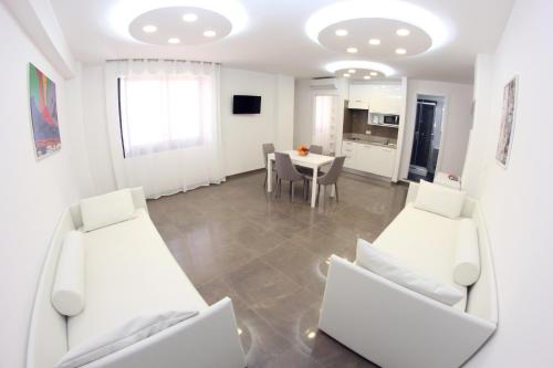 a living room with white furniture and a table at Mondo Suites Apartments in Naples
