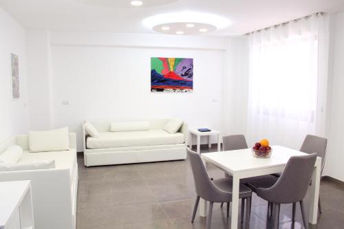 a white living room with a white table and chairs at Mondo Suites Apartments in Naples