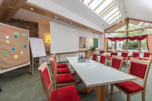 a dining room with a white table and red chairs at Hotel Lamm in Ostfildern
