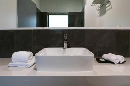 a white sink in a bathroom with towels on a counter at Birch Resort Port Douglas in Port Douglas