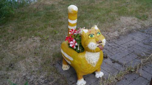 a statue of a cat with flowers in its mouth at Verlan Satumaa in Verla