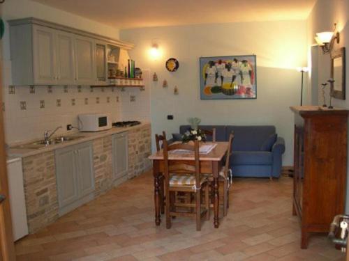 a kitchen and dining room with a table and a blue couch at La Piazzetta in Bettona
