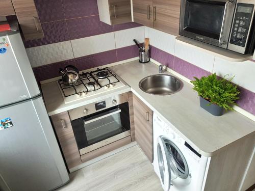 una pequeña cocina con fregadero y nevera. en Apartment on Rokossovskogo 11 en Kaliningrado