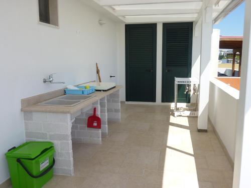 eine Küche mit einem Waschbecken und einem grünen Mülleimer in der Unterkunft DueAttici e un Pianoterra in Gallipoli