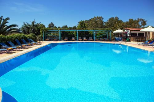 a large blue swimming pool with chairs and umbrellas at Aeolian Gaea Hotel in Skala Kallonis