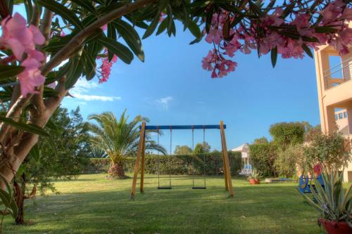 a swing in a park with pink flowers at Aeolian Gaea Hotel in Skala Kallonis