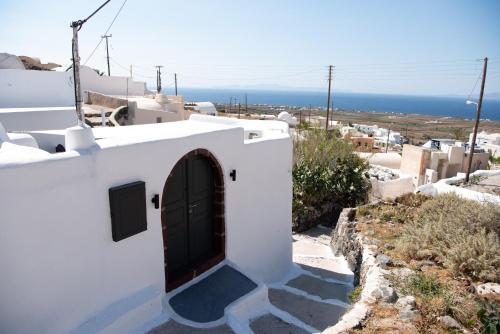 a door on a white building with a view of the ocean at Caves 1880 in Oia