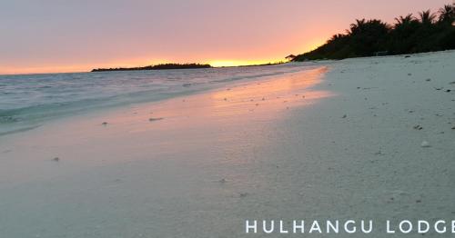 a beach with a sunset in the background at Hulhan'gu Lodge in Himmafushi