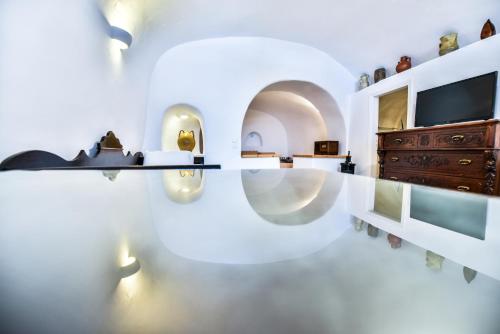a living room with a tv and a white wall at Caves 1880 in Oia