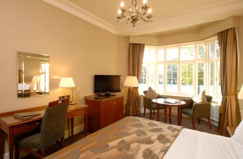 a hotel room with a bed and a desk and a television at Grovefield House Hotel in Slough