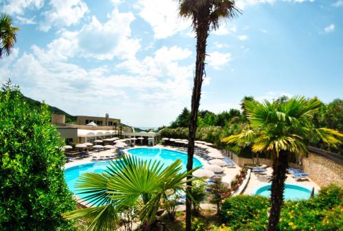 Blick auf den Pool des Resorts mit Palmen in der Unterkunft Le Torri Del Garda FamilySPA Resort in Torri del Benaco
