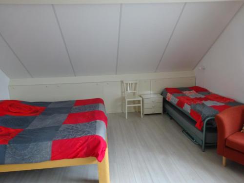 a attic bedroom with two beds and a chair at B&B Mendelts in Emmen