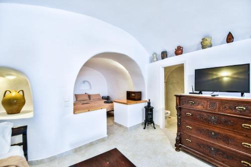 a living room with a tv and a dresser at Caves 1880 in Oia