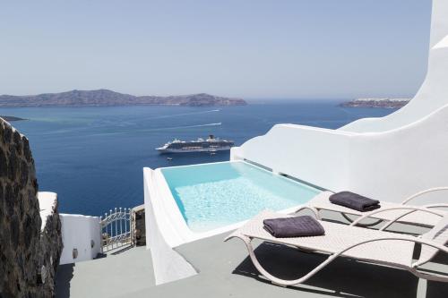 a balcony with a swimming pool and a boat in the water at Adamant Suites in Fira