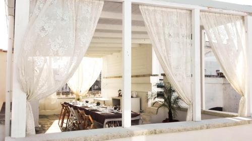 una sala da pranzo con tende bianche e tavolo di Il Borgo a Poggiardo