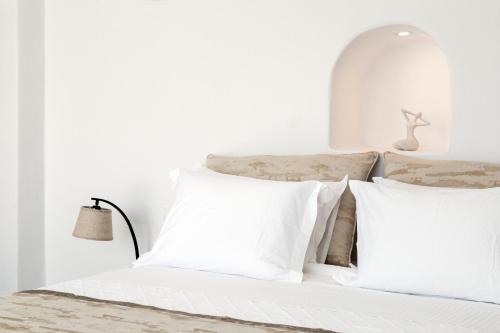 a white bed with white pillows on it at Adamant Suites in Fira