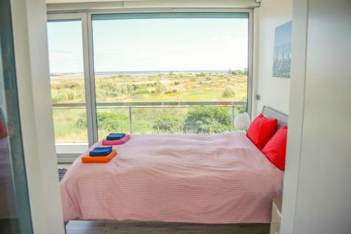 a bedroom with a pink bed and a large window at Palmares Beach, Golf & Dream in Lagos