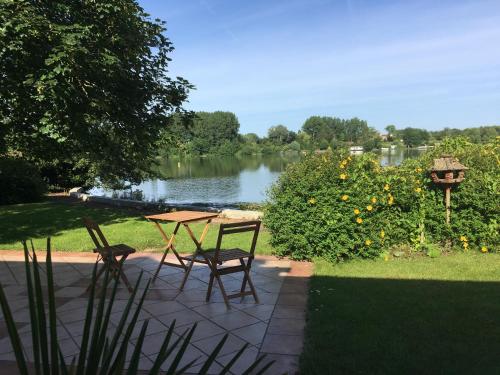 a patio with a table and chairs next to a lake at Les Secrets du Lac in Ardres