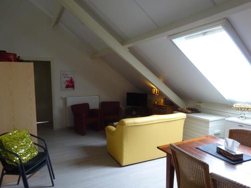 a living room with a yellow couch and a table at B&B Mendelts in Emmen