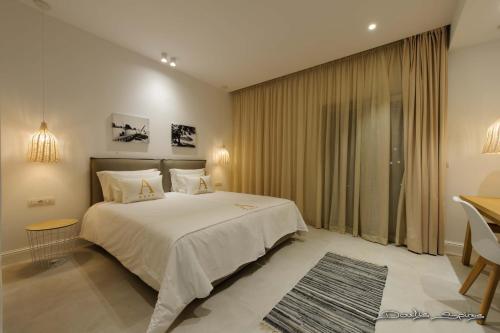 um quarto com uma grande cama branca e uma secretária em Alfa Hotel em Parga