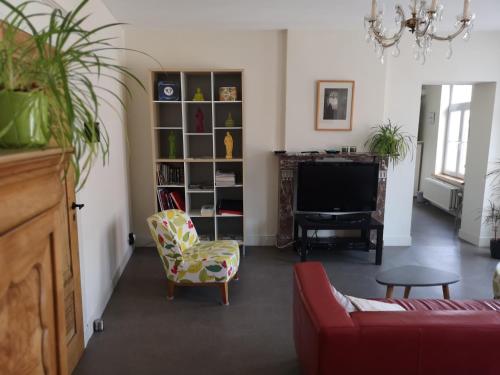 a living room with a red couch and a tv at Aux Herbes Folles in Herve